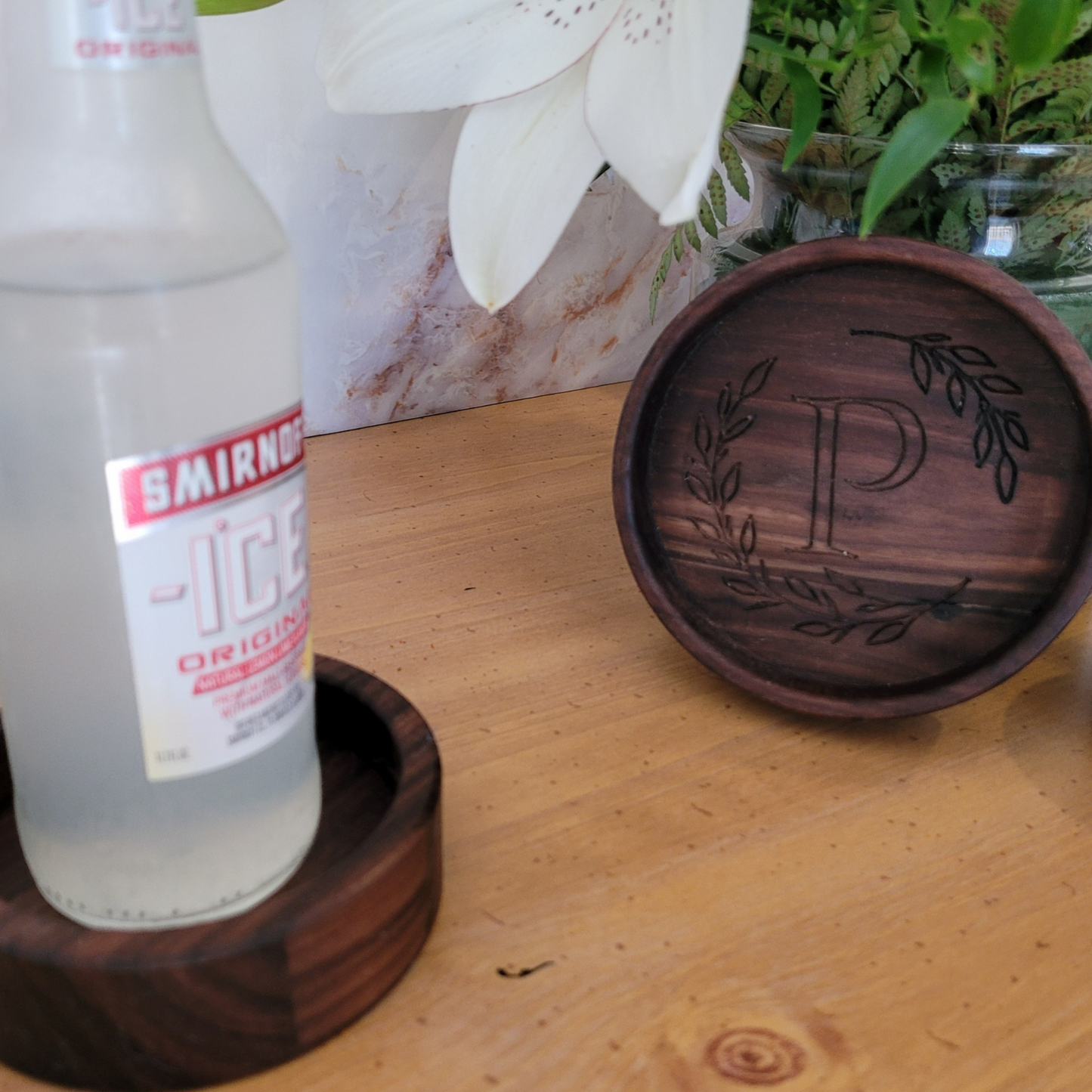 A rustic-style wooden coaster with engraved wreath and initial