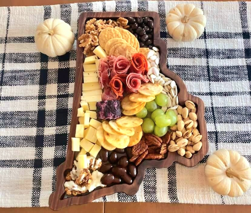 Rhode Island state-shaped wooden charcuterie board boasting a delicious arrangement of artisanal cheeses, grapes, and nuts