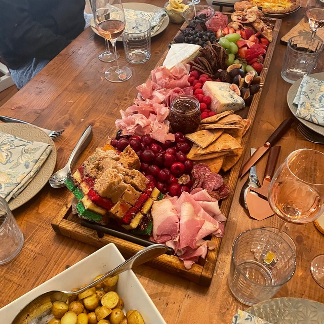 Wooden charcuterie board with an assortment of gourmet cheeses, cured meats, and fresh fruits